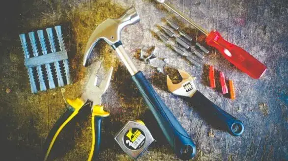 Collection of hand tools including hammer, screwdriver, and pliers in a workshop setting.