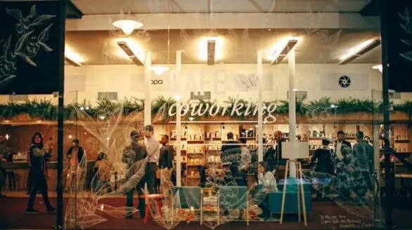 A cozy and bustling indoor coworking space with people engaged in work and conversation.