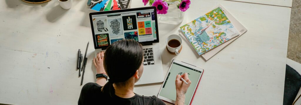 Artistic workspace featuring calligraphy and digital design on a tablet and laptop.