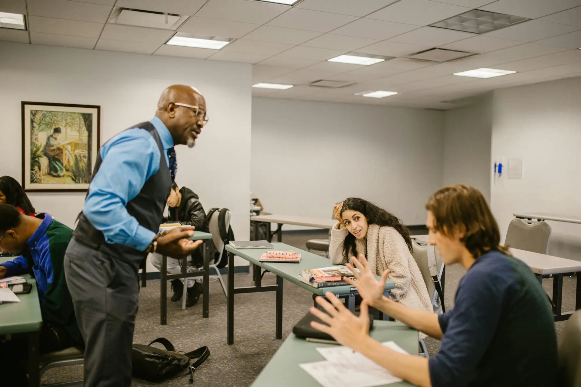 A professor interacts with college students during a lively classroom discussion.