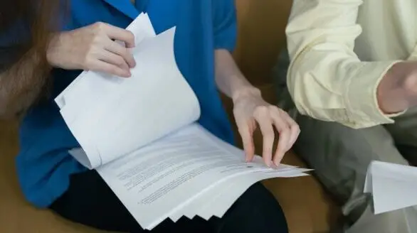 People in professional attire reviewing important documents together on a sofa.